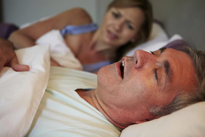 Woman awake in bed due to snoring husband may want to know what is sleep apnea