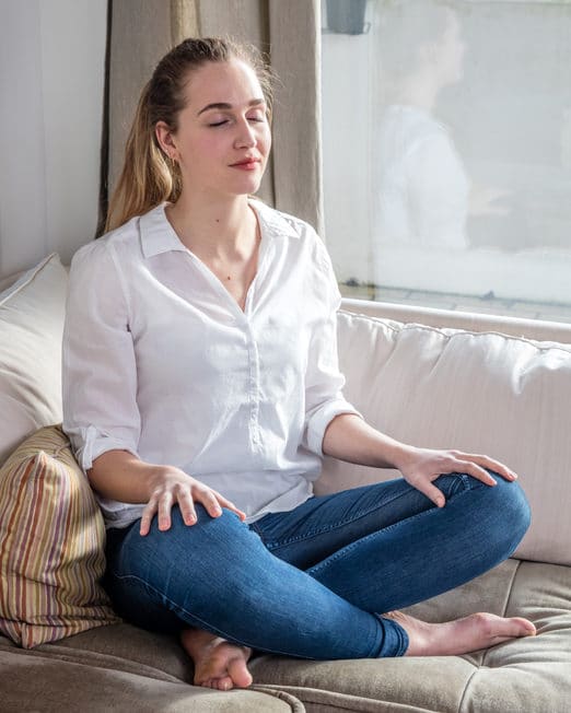 woman sitting on the couch and doing breathing exercises