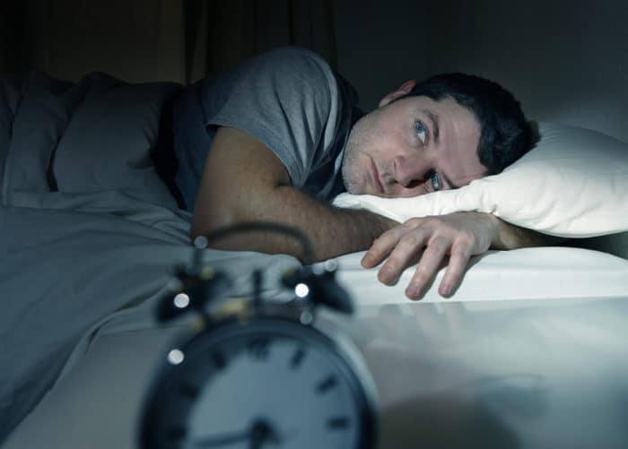 Insomnia is one of the most common sleep disorders Man wide awake in bed suffering from insomnia which is one of the many different sleep disorders