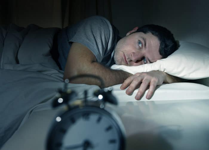 Man wide awake in bed suffering from insomnia which is one of the many different sleep disorders