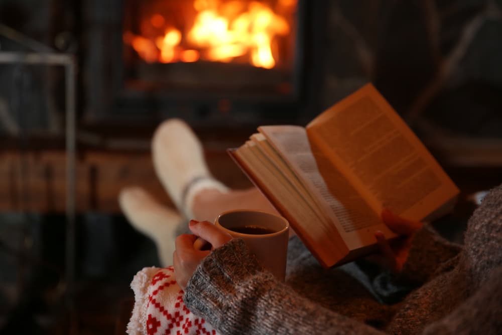 person reading book by fireplace