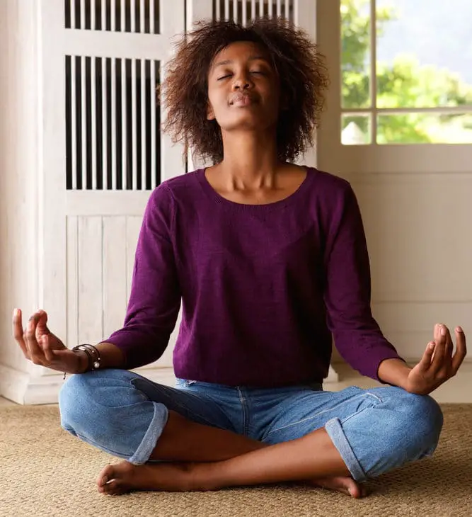 photo of lady meditating during the day for her sleep to stop waking up late for work