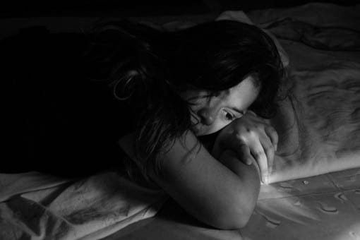 Does chronic pain keep you up at night wondering how to go to sleep? woman with chronic pain awake in bed wondering how to go to sleep