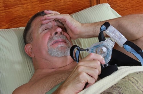 photo showing older male in bed with mask off because due to CPAP anxiety