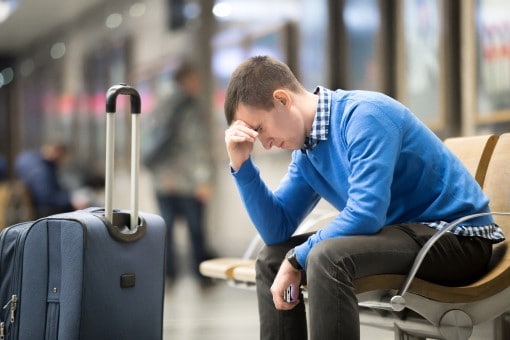 man sitting at airport feeling jet lagged who might need acupressure or acupuncture