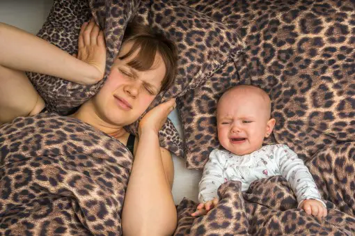 frustrated mom awake in bed with infant worried snoring woke the baby
