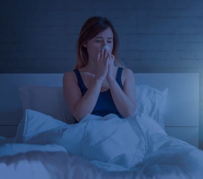 lady in bed wondering whether snoring is causing her nose bleeds