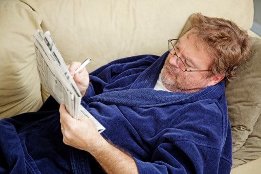 Man worried about coronavirus and a recession checking news paper instead of sleep 