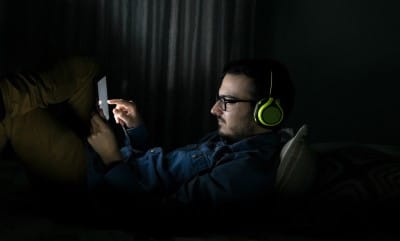 If you’re worried about coronavirus and a recession, late night binging on movies in bed will hurt your sleep Man worried about coronavirus and a recession watching movies in bed instead of sleep