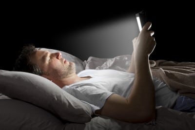 man in bed watching YouTube on bright electronic screen 