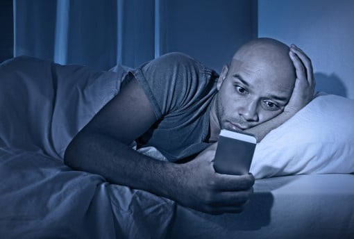  photo of man who woke up during the night checking smart phone