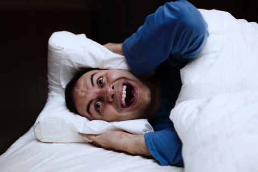 What’s the best fan for white noise for you? Read on... frustrated man awake in bed who wants the best fan for white noise