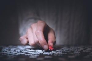 picture of man bored in bed at night working on a puzzle