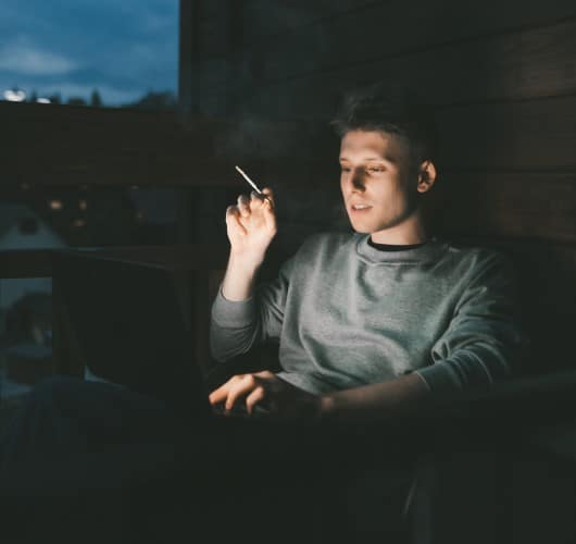 man on computer after waking up in the middle of the night to smoke