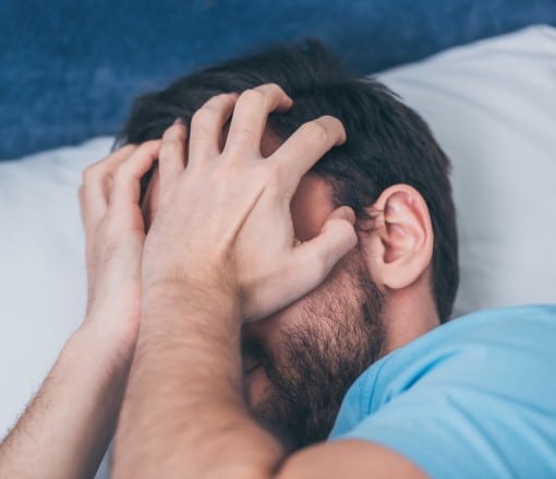 man frustrated in bed showing how people feel when CPAP stressing you out