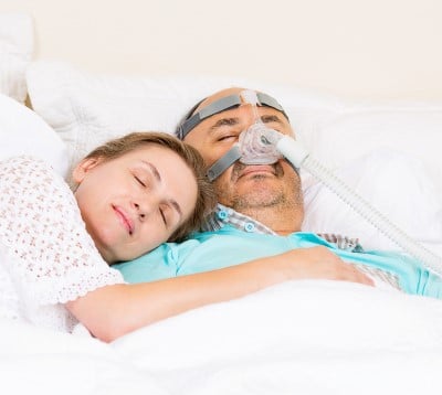 relaxed couple sleeping great together because CPAP is not stressing them out