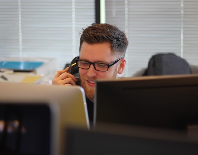 photo of coworker calling someone who slept through alarm for work