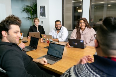 Getting more involved may help you survive photo of professional in meeting talking to coworkers