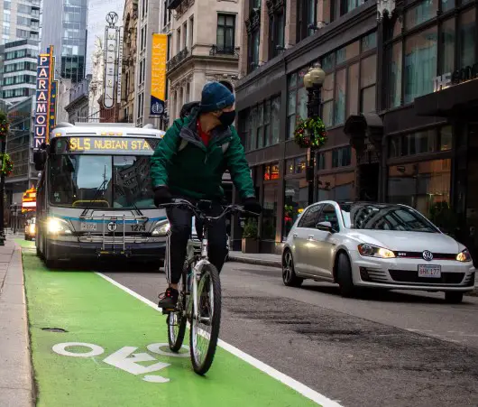 :  photo of city bus and person commuting on a bike