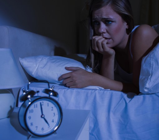Avoid consuming caffeinated foods and drinks too late in the day adult female awake in bed after eating a snack with caffeine