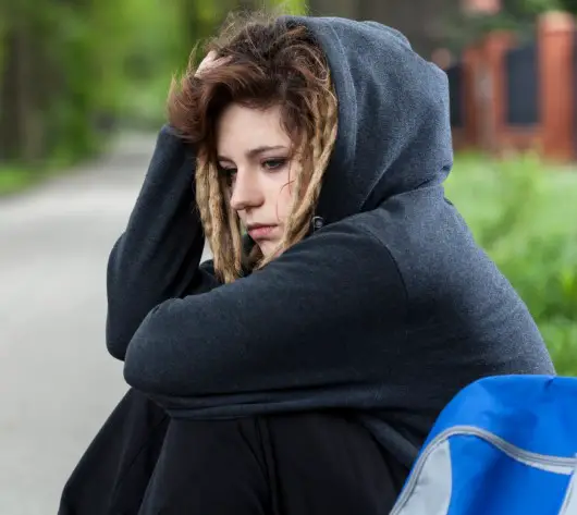 photo of depressed teen siting by road