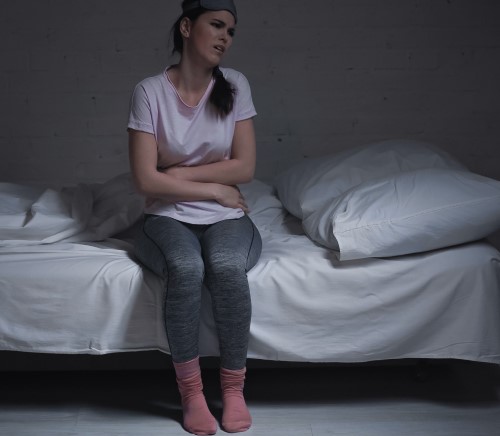 adult female awake in bed because of an upset stomach from holiday food