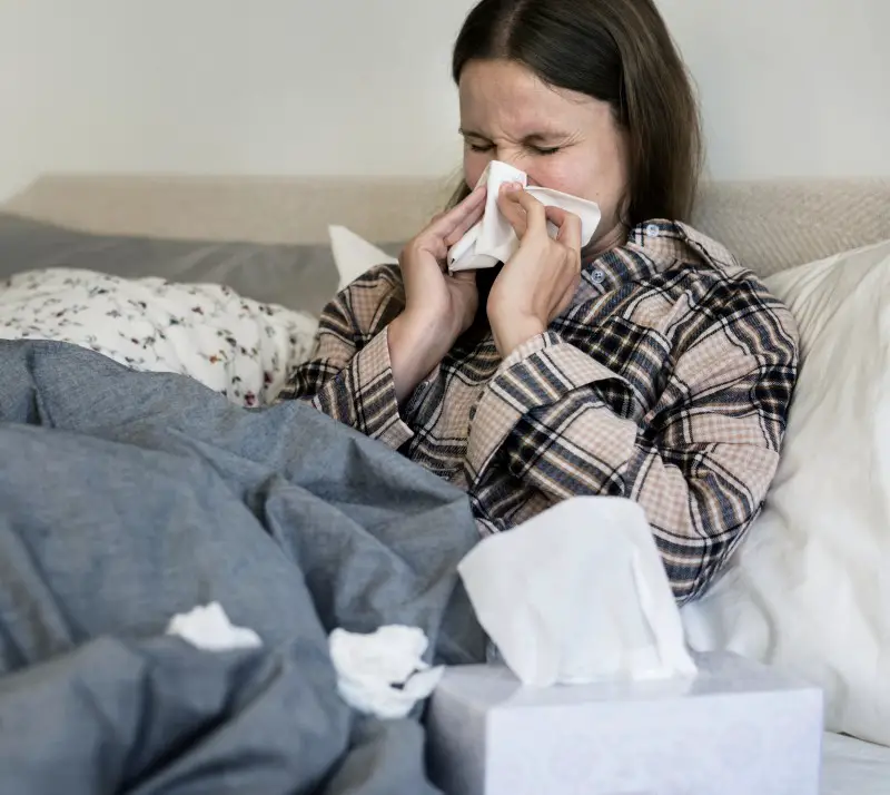 All too many people are losing sleep because of allergies photo of woman in bed blowing nose who can’t sleep because of allergies