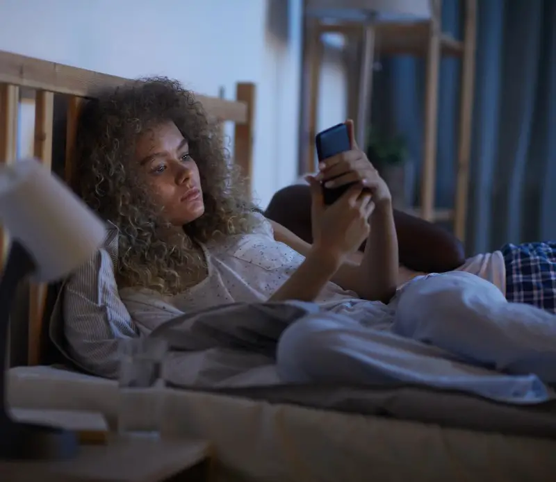 Beware of pitfalls when looking for a YouTube channel to fall asleep to photo of female in bed at night looking at YouTube on smartphone for something to fall asleep to