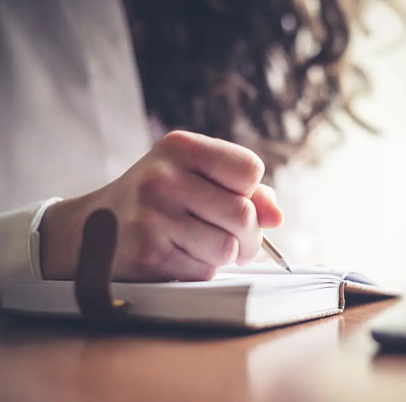 person using the extra hour from the fall daylight savings time change to organize their day in a notebook