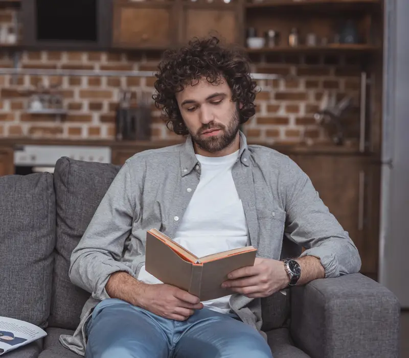 man sleepless after an argument reading a book on the couch